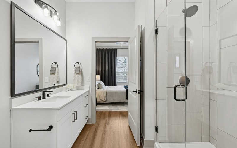 a bathroom with glass shower, large white vanity with quartz countertops